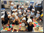 Children in a classroom wearing paper hats.