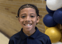 Smiling child with braided hair and balloons.