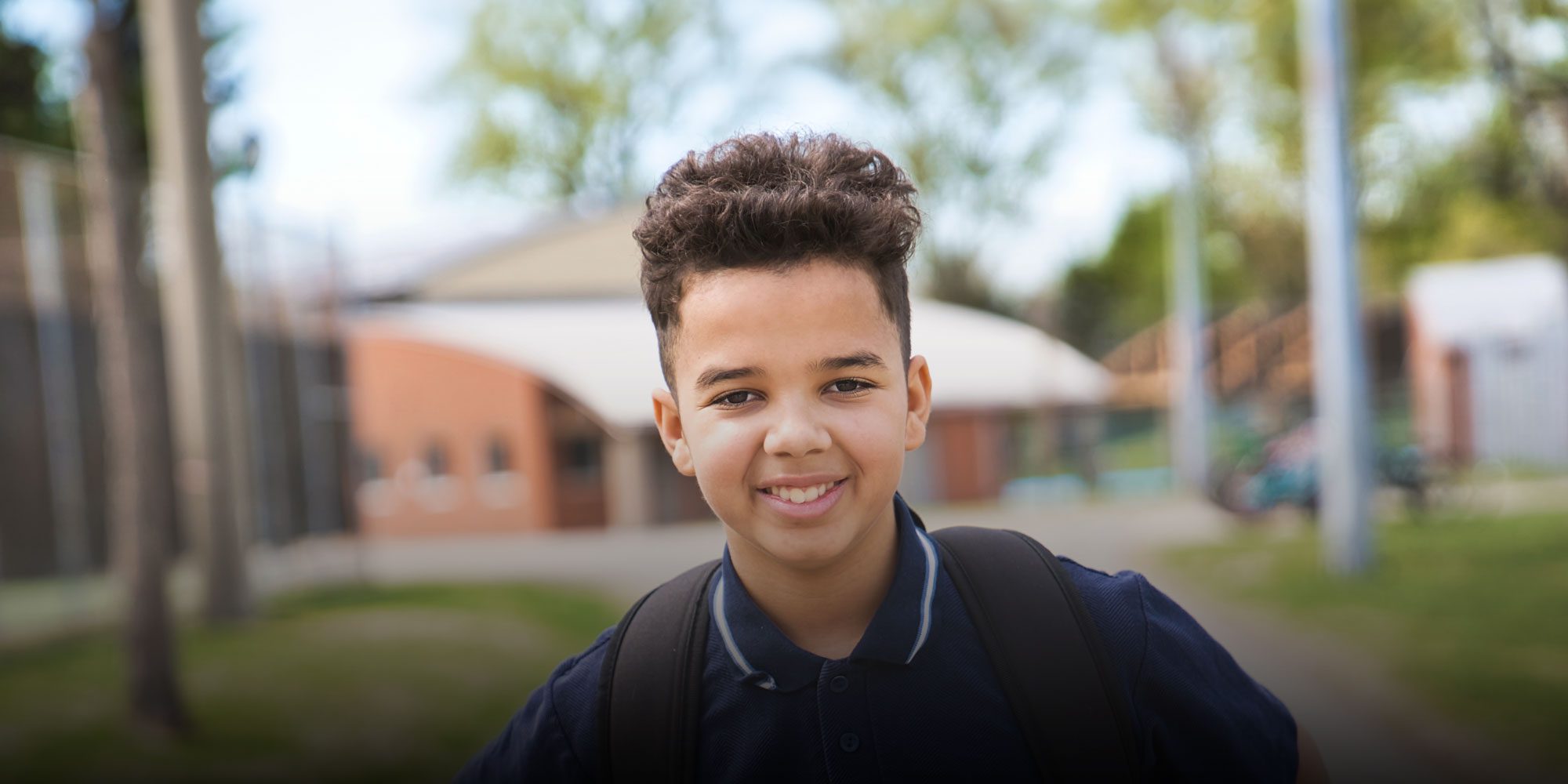 Smiling student standing outside with backpack